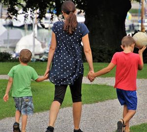 Finding a Babysitter on woman holds the hands of two boys