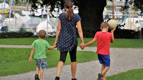 Finding a Babysitter on woman holds the hands of two boys