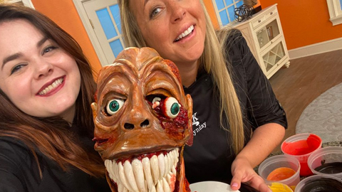 two women in front of zombie head cake