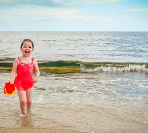 Beach Trip on a Budget. little girl in red bathing suit on the beach