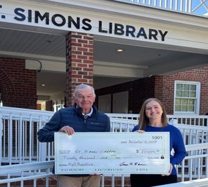 Discover the Literary Guild of St. Simons Island. an old man and a woman holding an oversized check