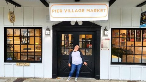 Pier Village Market. a woman standing in front of a white store